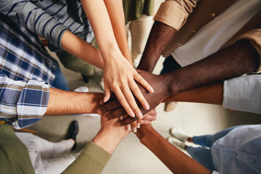 Cropped photo of multiracial people hands put on top of each other symbolizing unity.