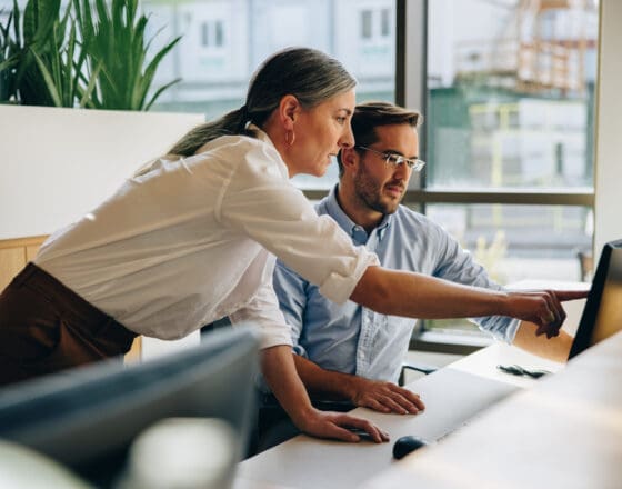 Women and man pointing at a screen together while in an office setting