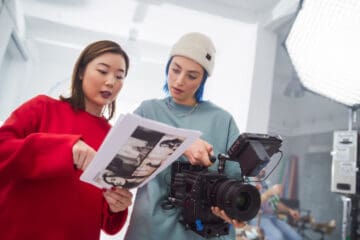 Two women looking at notes while handling a camera
