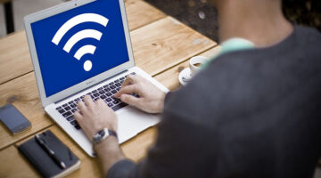 Person sitting with laptop. Screen shows Wifi Icon on it