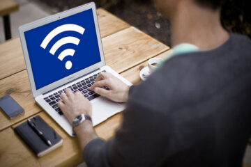 Person sitting with laptop. Screen shows Wifi Icon on it
