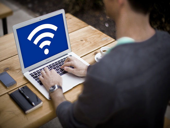 Person sitting with laptop. Screen shows Wifi Icon on it