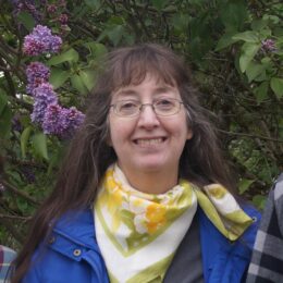 Becky Turnbull outside near lilac bush with yellow floral scarf