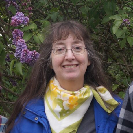 Becky Turnbull outside near lilac bush with yellow floral scarf