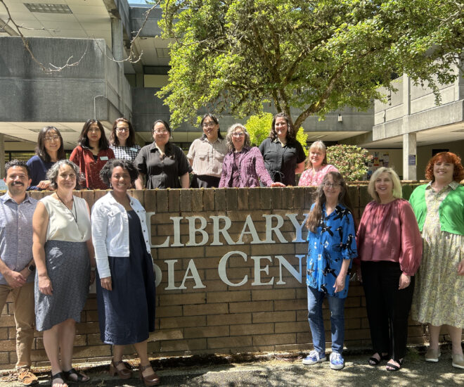 Diverse group of people standing outside Bellevue College Library Media Sign