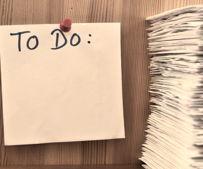 Note pinned to wall with To Do written on it. Stack of papers next to note.
