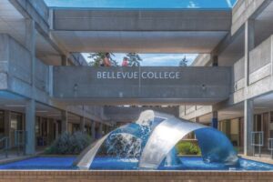 Bellevue College courtyard with a curved metal fountain sculpture beneath a walkway labeled ‘Bellevue College.