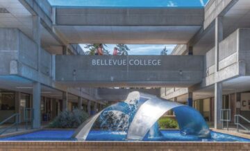 Bellevue College courtyard with a curved metal fountain sculpture beneath a walkway labeled ‘Bellevue College.