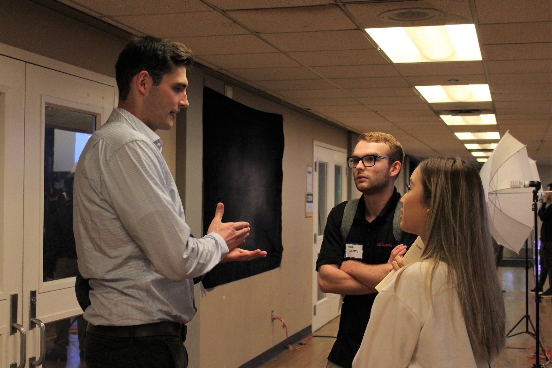 Three people talking in a hallway