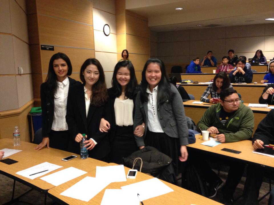 Four students standing next to a desk