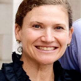 Smiling woman with hair pulled back wearing earrings.