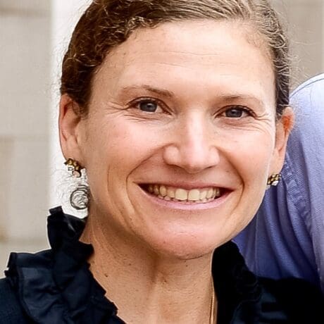 Smiling woman with hair pulled back wearing earrings.