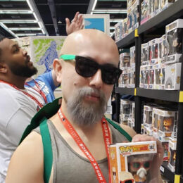 Man holding a boxed collectible figure in a store aisle.