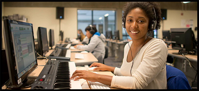 Bellevue College student sitting at computer and smiling looking at the camera