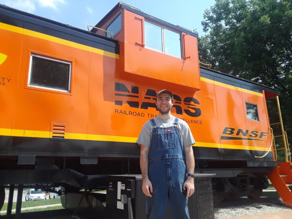 OLS alumni poses in front of a train car.