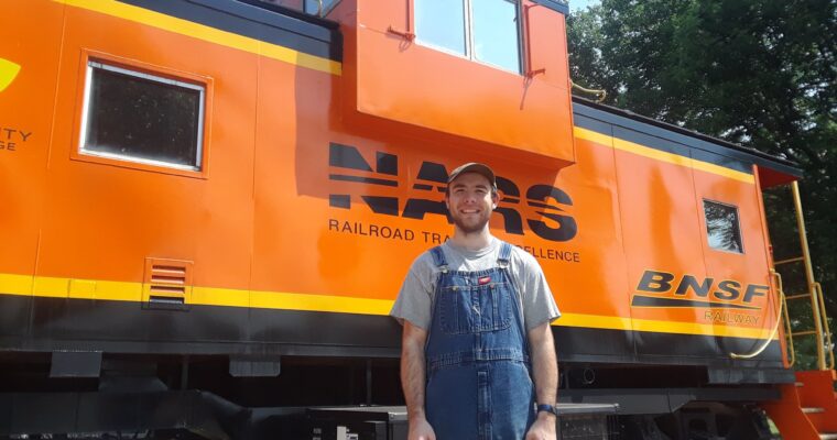 OLS alumni poses in front of a train car.
