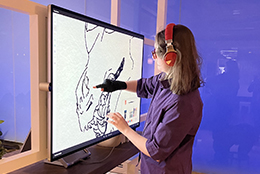 An OLS student draws on a large touch screen.