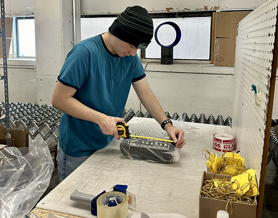 An OLS intern measures a product in a warehouse.