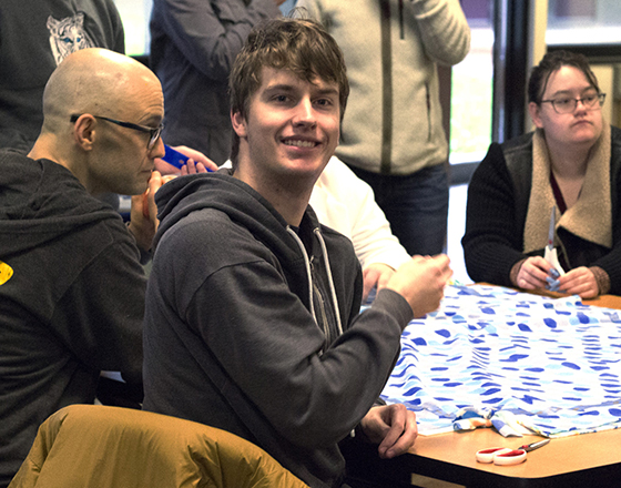 OLS students work on a group project while one smiles at the camera.