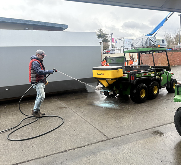 AN OLS intern washes an industrial vehicle in a car lot.