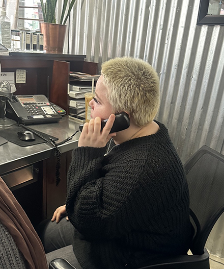 An OLS intern speaks on the phone at a reception desk.