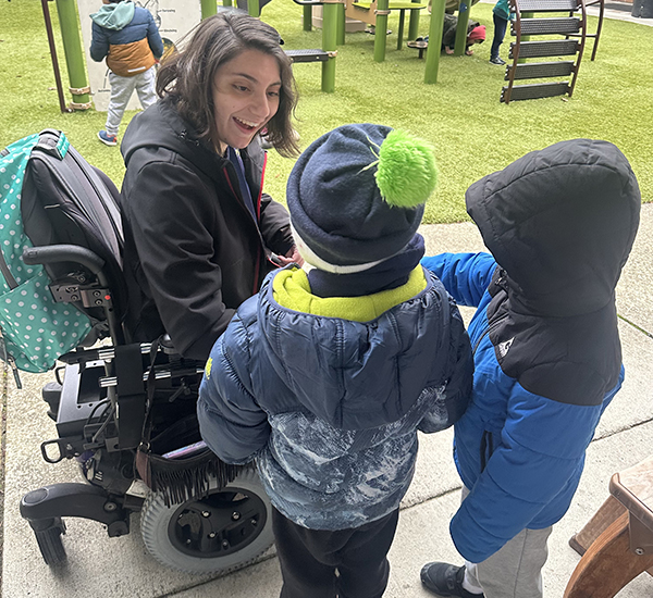 An OLS intern engages with small children on the playground at her internship workplace.