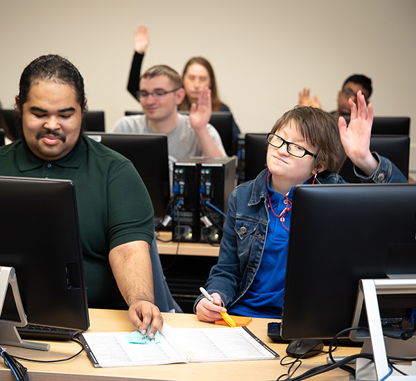OLS students engage with classroom instruction by taking notes and raising their hands.