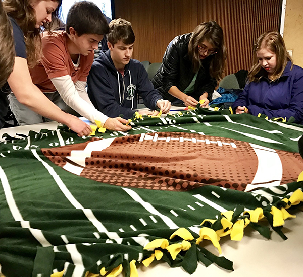 A group of OLS students makes a blanket as part of their service learning.