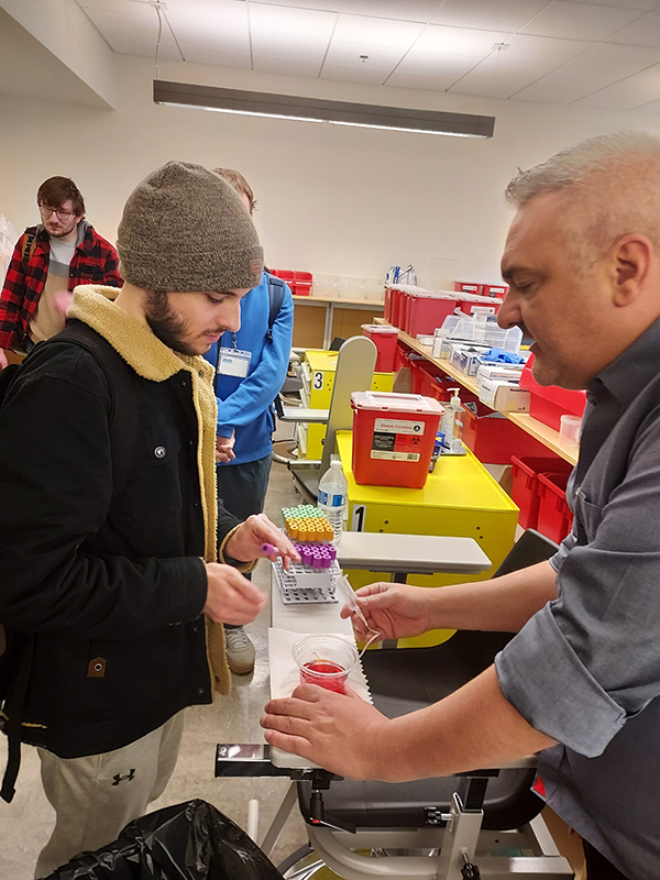 OLS students learn about collecting fluid samples in test tubes on the Health Sciences, Education and Wellness Institute tour.