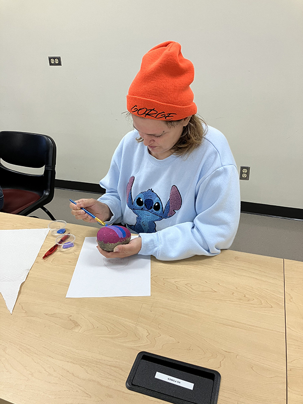 An OLS student paints kindness rocks.