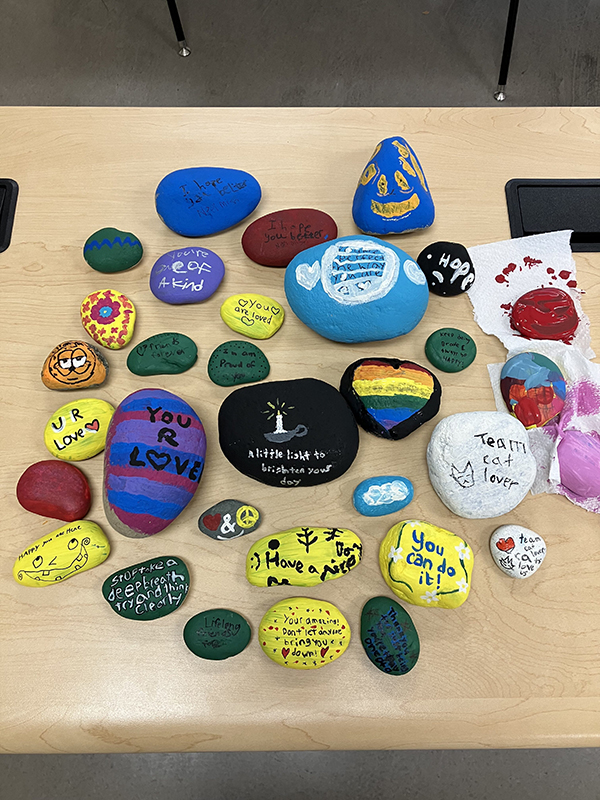 Handpainted kindness rocks are displayed on a table.