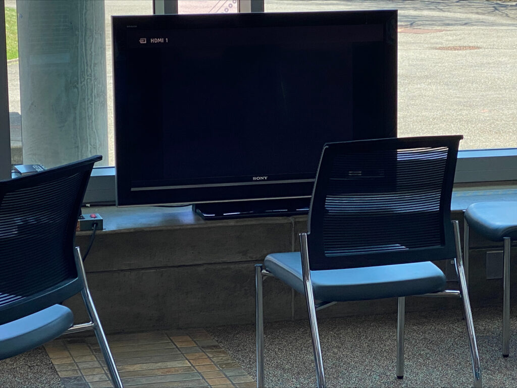 Chairs sit in front of a large-screen monitor.