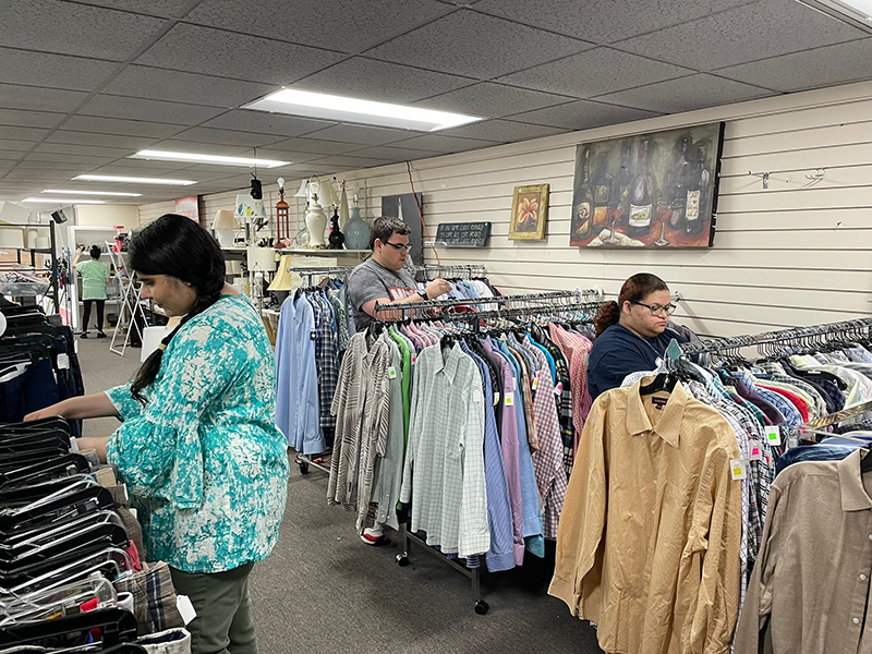OLS students hang clothing in a retail store.
