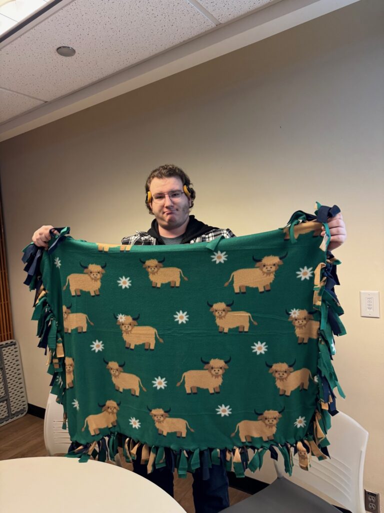 An OLS student displays a blanket made for Seattle Children's Hospital.