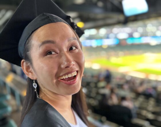 College graduate smiles in a cap and gown.
