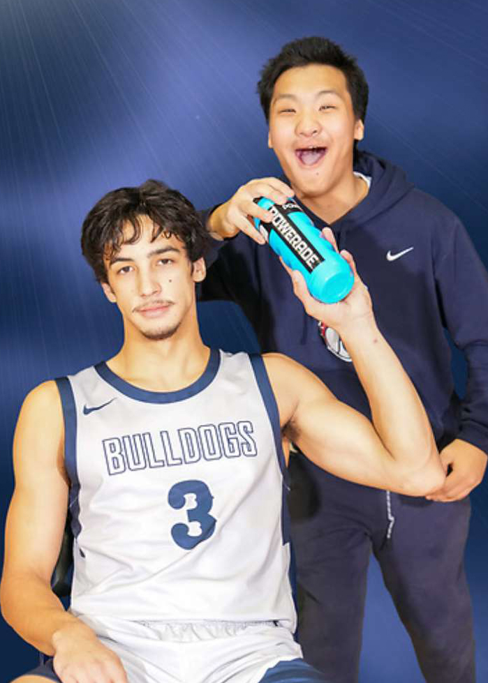 Logan Kassebaum hands a BC basketball player a water bottle over his shoulder.
