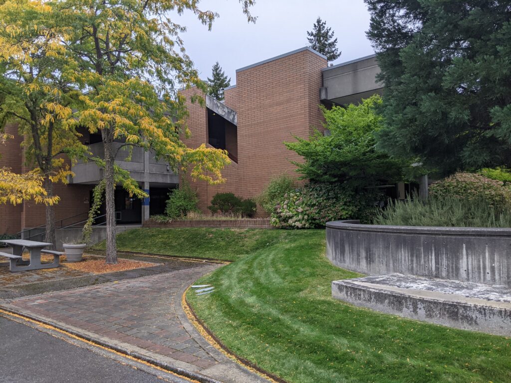 broad view of mural site 9 on exterior wall of A building, showing landscaping and trees to sides of mural site