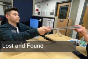 Thinh handing a student a computer at the public safety desk