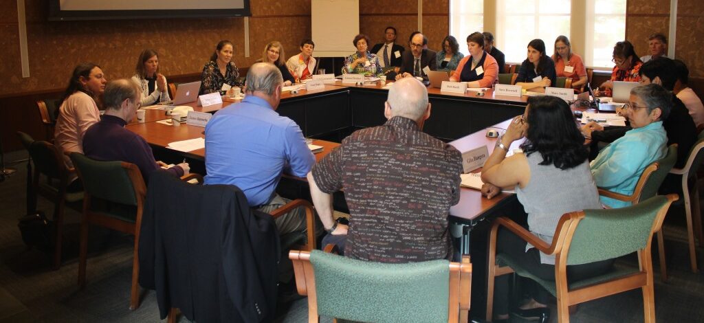 A meeting taking place with multiple people gathered around a table with nametags and notes
