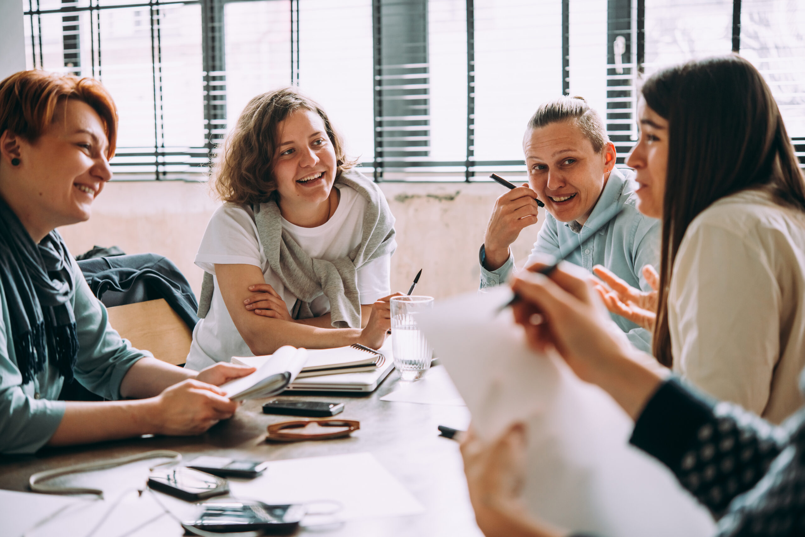 A group of people gathered around a table while smiling and writing down notes on a piece of paper.