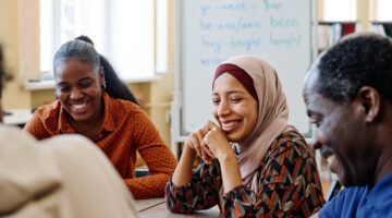 Group of modern immigrants sitting at table having fun laughing