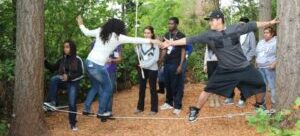 Students participating in a rope challenge course and trying to balance on a rope.