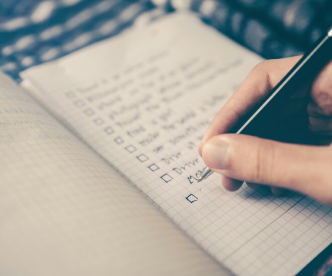 person marking things off a checklist in a journal