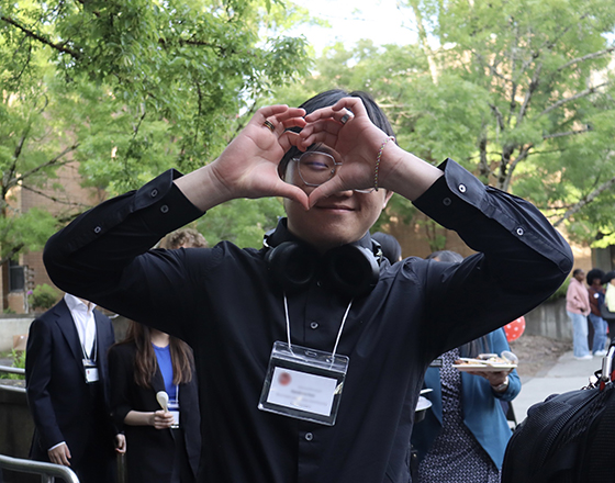 A student leader frames a heart with their fingers.