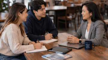 A female advisor meeting with two college students at a table.