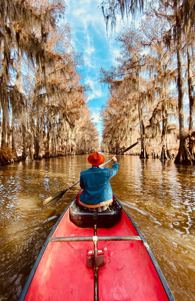 A boater guides a long boat downriver.