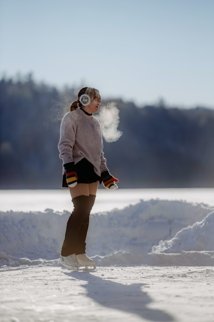 An ice skater on an outdoor lake breathes vapor on a cold day.