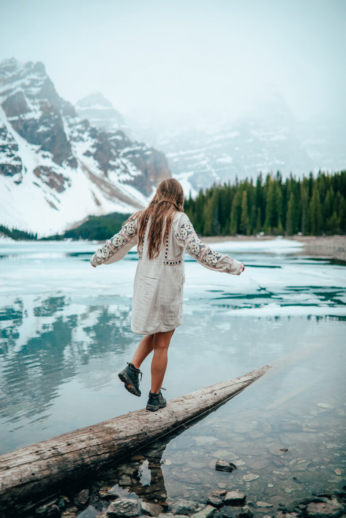 A hiker balances on a log that leads into river water.