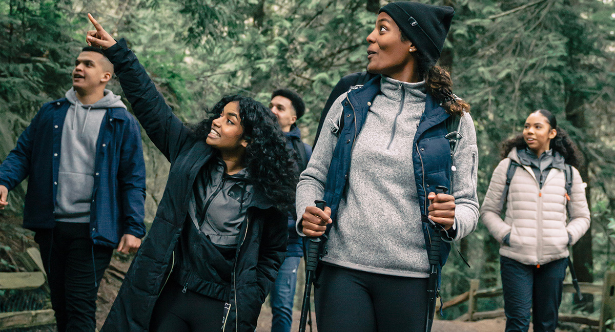 Hikers in a Pacific Northwest forest point at a wildlife sighting.