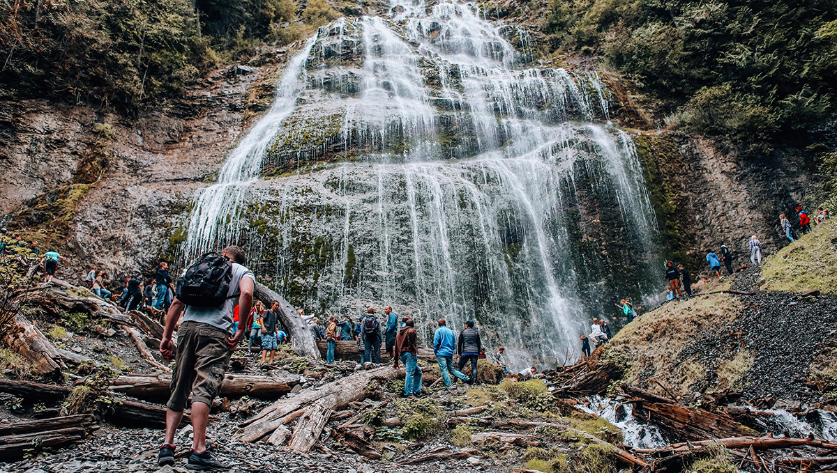 A group of hikers admire a large waterfall.